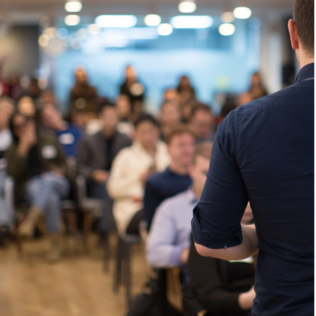 an image of a public meeting with the audience blurred out