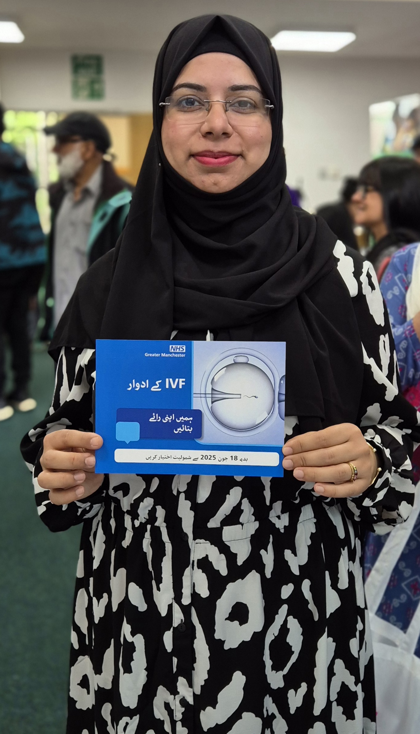 Person in a hijab holding an IVF postcard in Urdu